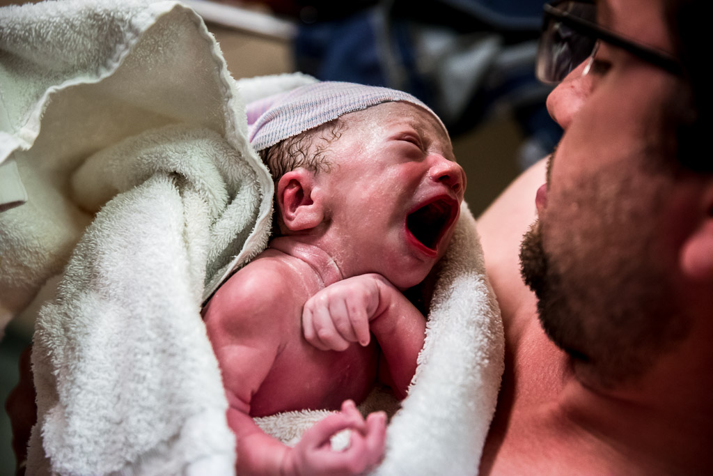 Papa buidelt met zijn pasgeboren zoon in het ziekenhuis van Leeuwarden gefotografeerd door Sandrinos Geboortefotografie uit Purmerend