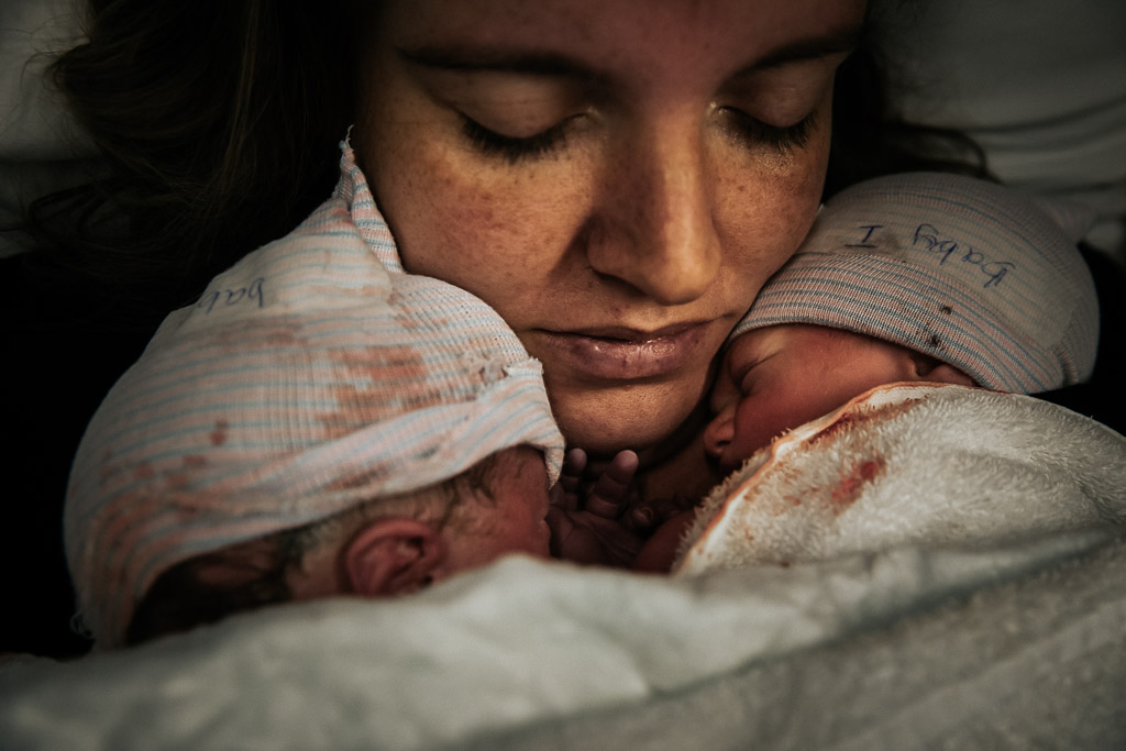 Trotse mama met haar pasgeboren tweeling op haar borst in het ziekenhuis van Leeuwarden gefotografeerd door Sandrinos Geboortefotografie uit Purmerend