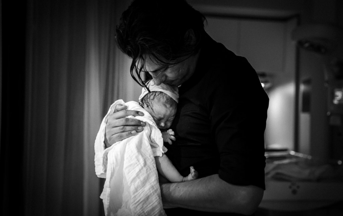 Papa met zijn pasgeboren dochter in zijn armen tijdens de geboortereportage in het Amsterdamse ziekenhuis
