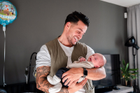 Papa kijkt liefdevol naar zijn pasgeboren dochter tijdens een kraamreportage aan huis in Almere