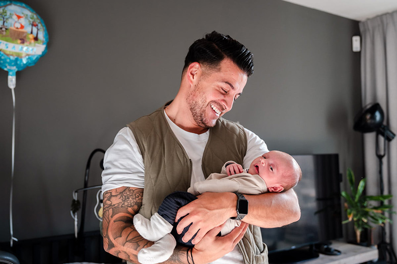 Papa kijkt liefdevol naar zijn pasgeboren dochter tijdens een kraamreportage aan huis in Almere