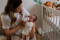 Mama geeft haar dochter de fles tijdens de kraamreportage aan huis in Purmerend