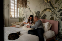 Papa en mama relaxen met hun baby op bed tijdens de kraamreportage in Purmerend