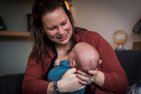 Mama kijkt liefdevol naar haar baby tijdens de kraamreportage