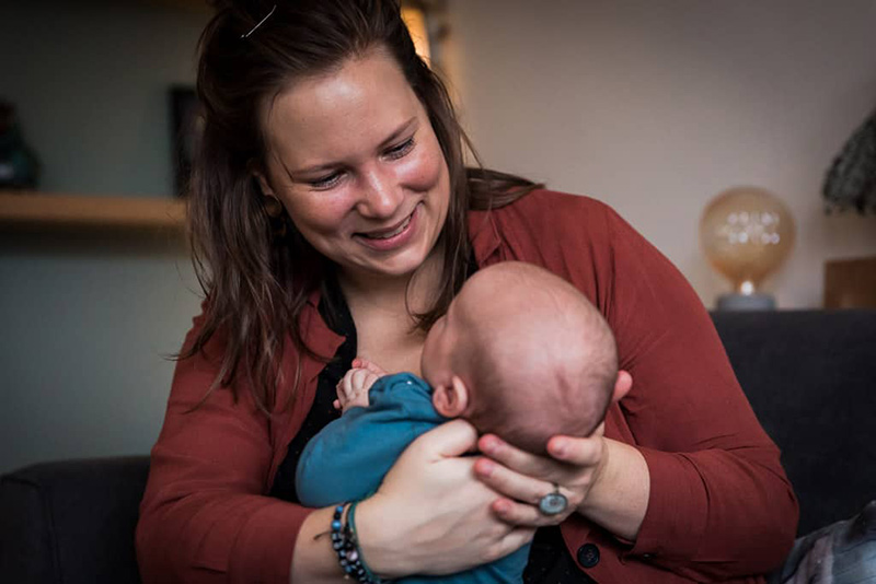 Mama kijkt liefdevol naar haar baby tijdens de kraamreportage