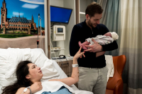 Geboortereportage Den Haag-13 Papa houdt zijn derde kindje liefdevol vast in het HMC in Den Haag terwijl mama vanuit haar kraambed toekijkt