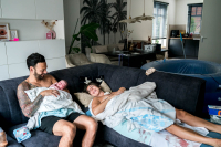 Geboortereportage Veenendaal-15 Mama ligt op de bank bij te komen na de thuisbevalling terwijl papa zijn dochter voor het eerst vasthoudt