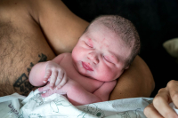 Geboortereportage Veenendaal-16 Een prachtige close-up van een pasgeboren baby die lekker warm bij papa ligt