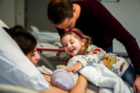 Het oudere zusje raakt vol liefde haar baby broertje aan