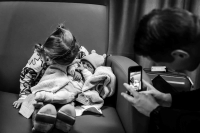 Papa maakt een foto met zijn mobiel van zijn dochter en pasgeboren zoon