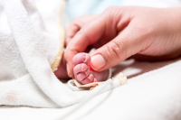 Geboorte-VBAC-6 Papa houdt het babyvoetje van zijn zoontje vast